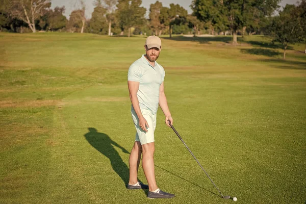 serious golfer in cap with golf club, golf player.