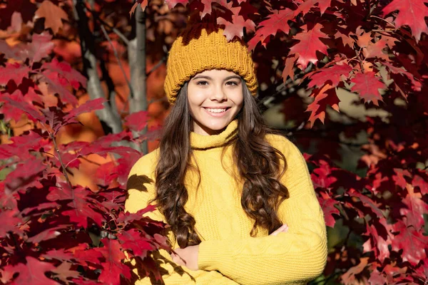 Teenager girl on autumn fall background. smiling kid in hat at autumn leaves on natural background.
