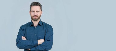 Kendine güvenen bir adam günlük gömlek giyer kolları çapraz gri arka plan, resmi olmayan kıyafetler, fotokopi alanı. İnsan yüzü portresi, kopyalanmış pankart
