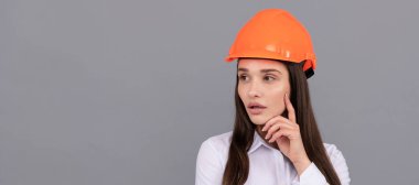 Güvenlik kasketi ve gri arka planda beyaz gömlekli düşünceli bir kadın, müteahhit. İzole edilmiş yüz portresi, taklit alanı olan pankart