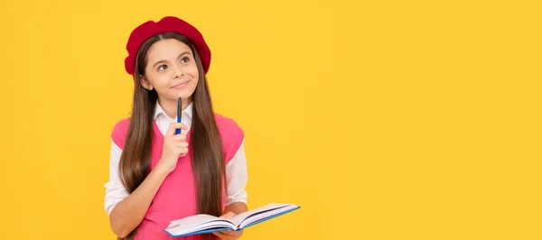thinking teen school girl in french beret making notes in notepad. Portrait of schoolgirl student, banner header. School child face isolated panorama background with copy space