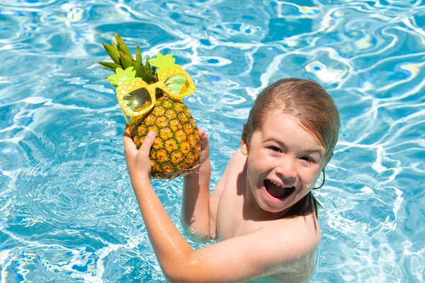 Child in swimming pool playing in summer water. Vacation and traveling with kids. Cute little boy swim on watter pool in the summer. Kids beach fun. Funny pineapple fruit for children
