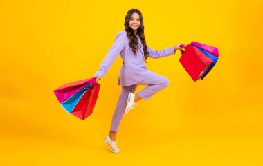 Stylish teen girl with shopping sale bags. Run and jump. Kid holding purchases