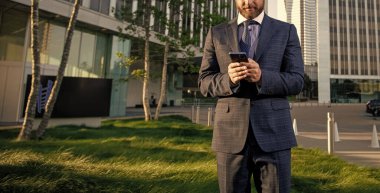 Takım elbiseli işadamı ofis dışında akıllı telefondan konuşuyor, pazarlık yapıyor..