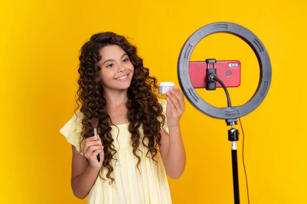 Teenager blogger making video, child vlogger influencer record content. Child blogger records video on mobile phone using ring video lamp. Happy teenager, positive and smiling emotions of teen girl