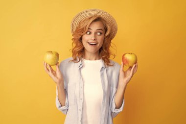 Şaşırmış genç kadın yaz şapkalı kıvırcık saçlı elma ve meyveli..