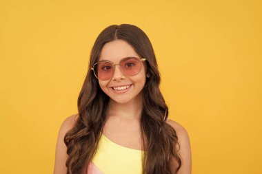 Plaj partisi. Yaz tatili. Güzel portre yüzü. Uzun saçlı çocuk gözlük takıyor. Sarı arka planda kıvırcık saçlı mutlu genç kız. çocukluk mutluluğu. çocuk yaz modası.