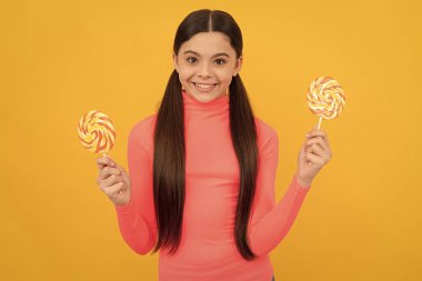 Bayıldım. Çubukta şeker. Karamelli şeker dükkanı. Tatlı çocukluk hayatı. Genç diş bakımı. Tatlı düşkünü. Lezzetli. Mutlu kız lolipopu tutar. Lolipop çocuk. Uzun saçlı çocuk lolipopu tutuyor..