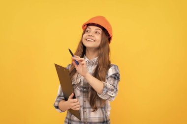 Çocukluk gelişimi. Doğum günün kutlu olsun. Gelecekteki kariyerim. Kasklı genç kız notlar alıyor. İnşaatçı çocuk klasöre yazıyor. Bina ve inşaat. Yoğunlaştırılmış çocuk işçisi sıkı tutuş panosu takıyor.