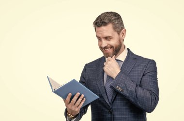 İş adamı kılığındaki bir iş adamı iş raporlarını beyaz not defterinde okurken şaşırdı..