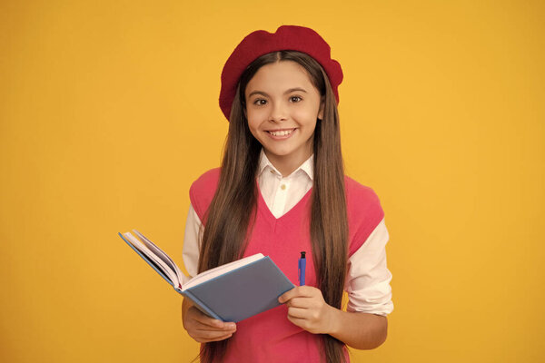 счастливая школьница в французском берете делает заметки в блокноте планировщика или блокноте, школе.