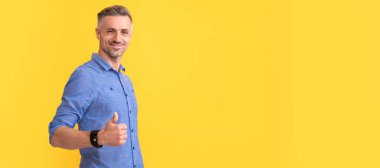 İnsan yüzü portresi, fotokopi alanı olan pankart. Saçları ağarmış gülümseyen olgun bir adam sarı arka planda baş parmağını gösteriyor, kopyalama alanı, başarı