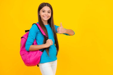 Happy teenager portrait. Back to school. Teenage school girl ready to learn. School children on yellow isolated background. Smiling girl