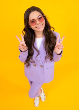 Sarı izole edilmiş arka planda günlük kıyafetlerle çekici, neşeli, genç kız çocuğu.