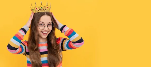 happy teen girl in glasses wear princess crown on yellow background, prom. Child queen princess in crown horizontal poster design. Banner header, copy space