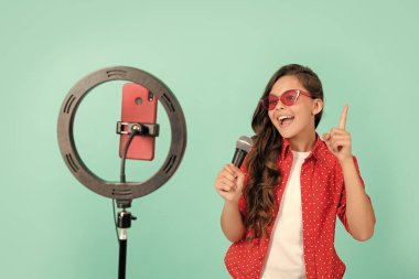 Güneş gözlüklü çocuk şarkıcının selfie, mikrofon ve vokal ile çevrimiçi video blogunda şarkı söylemesinden esinlenerek neşeli..