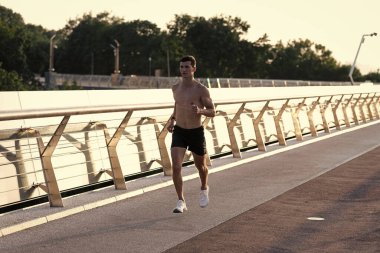 Kaslı gövdesiyle koşan atletik bir adam..