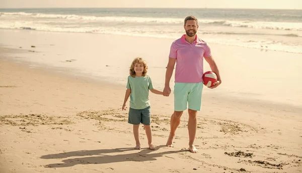 daddy with kid boy on summer day. weekend family day. dad and child having fun outdoors. childhood and parenting. family holidays. sport activity. happy father and son walk with ball on beach.