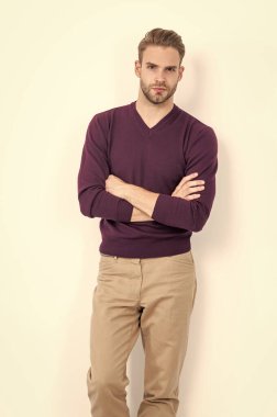 Rahat ama şık ol. Yakışıklı adam kollarını çapraz tutarak beyazın üzerinde soyutlanmış olarak duruyor. Moda dolabı. Sıradan bir tarz. Moda erkek giyim. Erkek gardırobu. Rahat olmak şarttır..