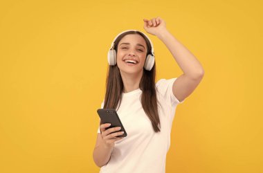 Kablosuz kulaklıkla giyin. Modern eğitim çevrimiçi. İletişim teknolojisi. Akıllı telefondan kadın sohbeti. Müzik dinliyordum. Etkileyici bloglar. Kulaklıklı neşeli kız..
