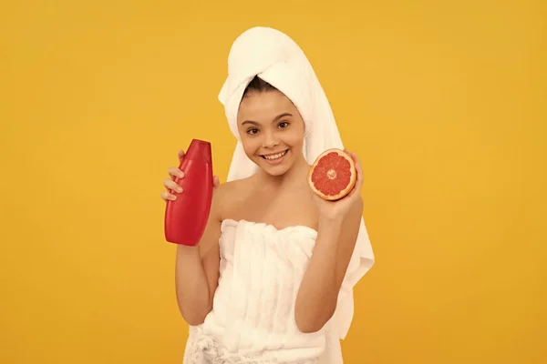 Lachend Kind Handdoek Met Grapefruit Shampoo Fles Gele Achtergrond — Stockfoto