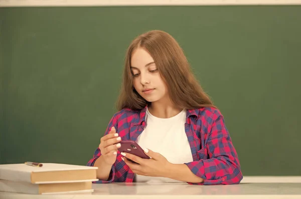 教育应用程序 孩子们在课堂上在线聊天 九月一日 儿童打字和发短信 短信和即时通讯 现代通信技术 忙碌的少女博主使用智能手机 回学校去 — 图库照片