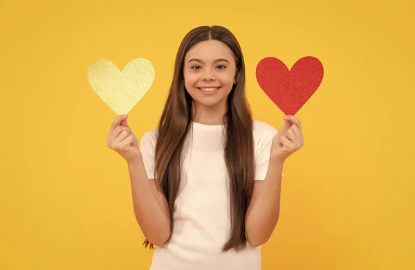 happy valentines day. be my valentine. teen girl on yellow background. love present. smiling kid with love romantic gift. sweetheart. valentines sale. portrait of child with heart.