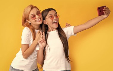 Online iletişim. Anne ve çocuk blogcuları. Mutlu kadın ve kız gözlüklü akıllı telefonlu selfie çekiyorlar. Selfie ailesi. Modern hayat. mobil teknoloji. Görüntülü arama yapıyorum. anne ve kız vlogging.