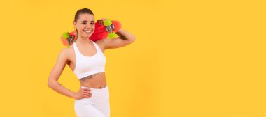 Enjoying life on penny board. Skater girl yellow background. Happy athletic girl hold pennyboard. Woman isolated face portrait, banner with mock up copyspace