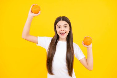 Excited teenager portrait. Teenage girl holding a grapefruit on a yellow background. Amazed girl