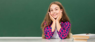 happy child sit at school on blackboard background, knowledge day. Banner of schoolgirl student. School child pupil portrait with copy space