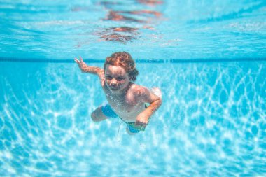 Underwater kids swims in pool, healthy child swimming and having fun under water