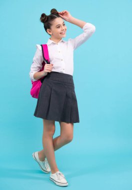 School girl in school uniform with backpack. Teenage girl student on blue isolated background. Learning knowledge and kids education concept