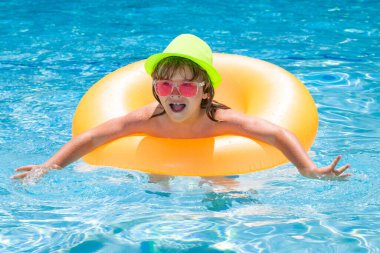 Child splashing in swimming pool. Active healthy lifestyle, swim water sport activity on summer vacation with child. Child in water play with inflatable toy ring