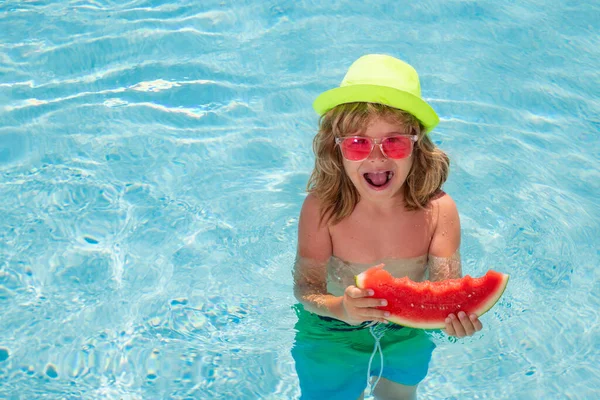 Child eating watermelon in swimming pool. Active healthy lifestyle