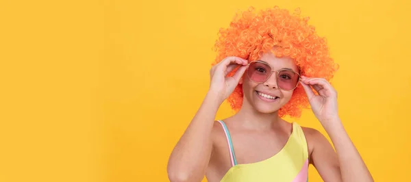 funny kid in curly clown wig. having fun. child wear sunglasses and swimsuit. Funny teenager child on party, poster banner header with copy space