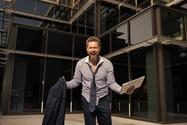 Sinirli iş adamı bilgisayar ve ceketle öfke içinde bağırıyor, iş çöküyor..