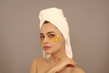 En iyi bakımı. Havlu bantlı genç bir kadın. Kaplıcada güzel bir gün. Altın anti-yorgunluk maskesi takıyorum. Kız göz torbalarını küçültür. Cilt bakımı. Yüz kolajeni kozmetiği. Nemlendirici cilt. kozmetoloji.