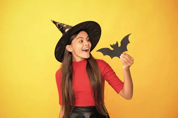 Positivo Adolescente Chica Usando Bruja Sombrero Celebración Murciélago Amarillo Fondo — Foto de Stock