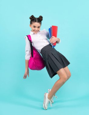 Kitap ve defter ile liseli kız çocuğu. İzole edilmiş mavi bir geçmişi olan genç bir öğrenci. Öğrenme ve bilgi. Git çalış. Eğitim konsepti. Mutlu ergen, pozitif ve gülümseyen duygular
