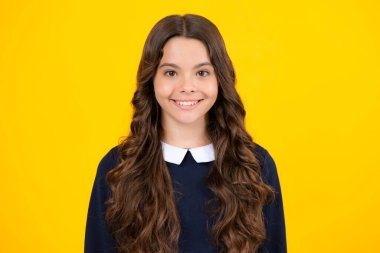 Portrait of cute positive little girl isolated on yellow background. Attractive caucasian child smiling and looking at camera