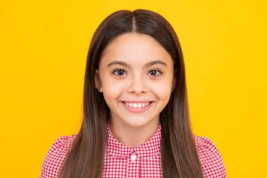 Portrait of cute positive little girl isolated on yellow background. Attractive caucasian child smiling and looking at camera