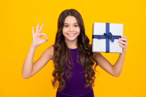 Child with gift present box on isolated background. Presents for birthday, Valentines day, New Year or Christmas. Happy girl face, positive and smiling emotions