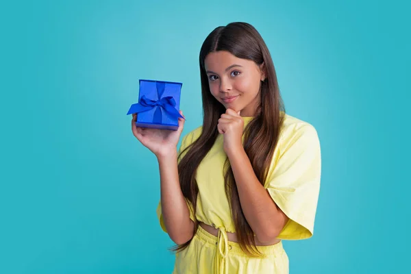 Child with gift present box on isolated background. Presents for birthday, Valentines day, New Year or Christmas. Happy girl face, positive and smiling emotions