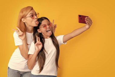 Mutlu anne ve çocuk akıllı telefondan selfie çekiyor. Barışı gösteriyor, blog yazarı..