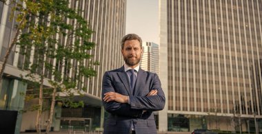 Ofis dışında takım elbiseli, karizmatik, olgun iş adamı gülümsüyor..
