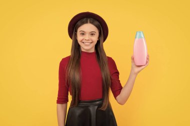 happy teen girl long hair with body lotion on yellow background, shower gel.