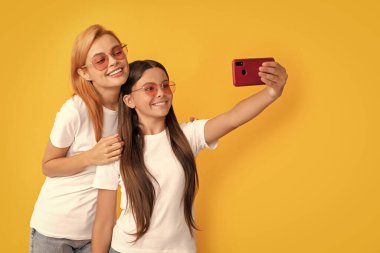 Anne ve çocuk blogcuları. Güzel kadın ve kız akıllı telefonla selfie çekiyorlar. Selfie ailesi. Modern hayat. mobil teknoloji. Görüntülü arama yapıyorum. Anne-kız vloglama. çevrimiçi iletişim.