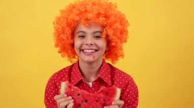 laughing teen girl in orange hair wig biting water melon slice, vitamin.