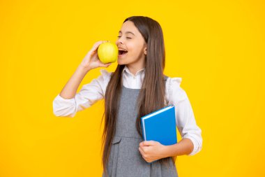 Okula dönelim. Liseli kız, sarı izole stüdyo geçmişi üzerine kitap tutuyor. Okul ve eğitim kavramı. Okul üniformalı ergen kız.